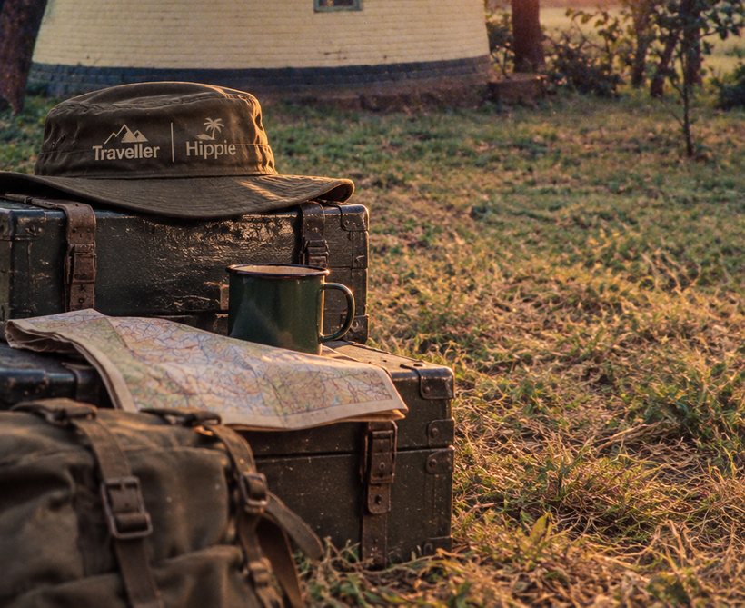 A worn bush hat, an old ammunition box, a map and an enamel mug at sunset.